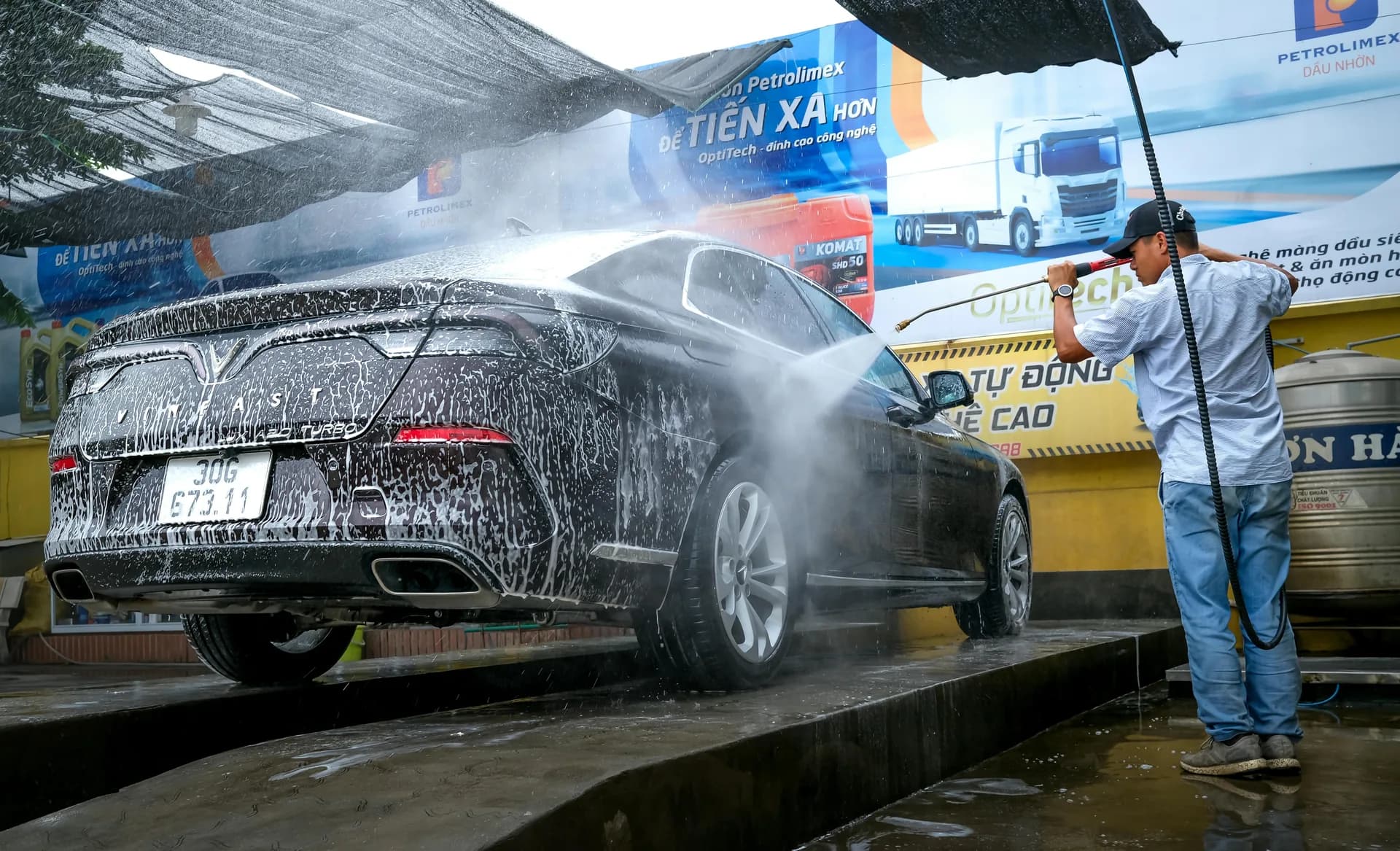 A car being pressure-washed at a vehicle service bay