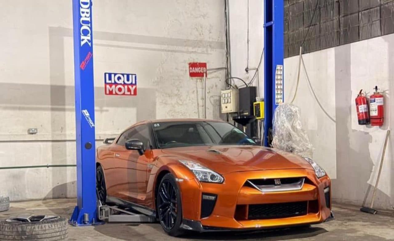Orange Nissan GT-R on a Roadbuck two-post lift inside a professional workshop
