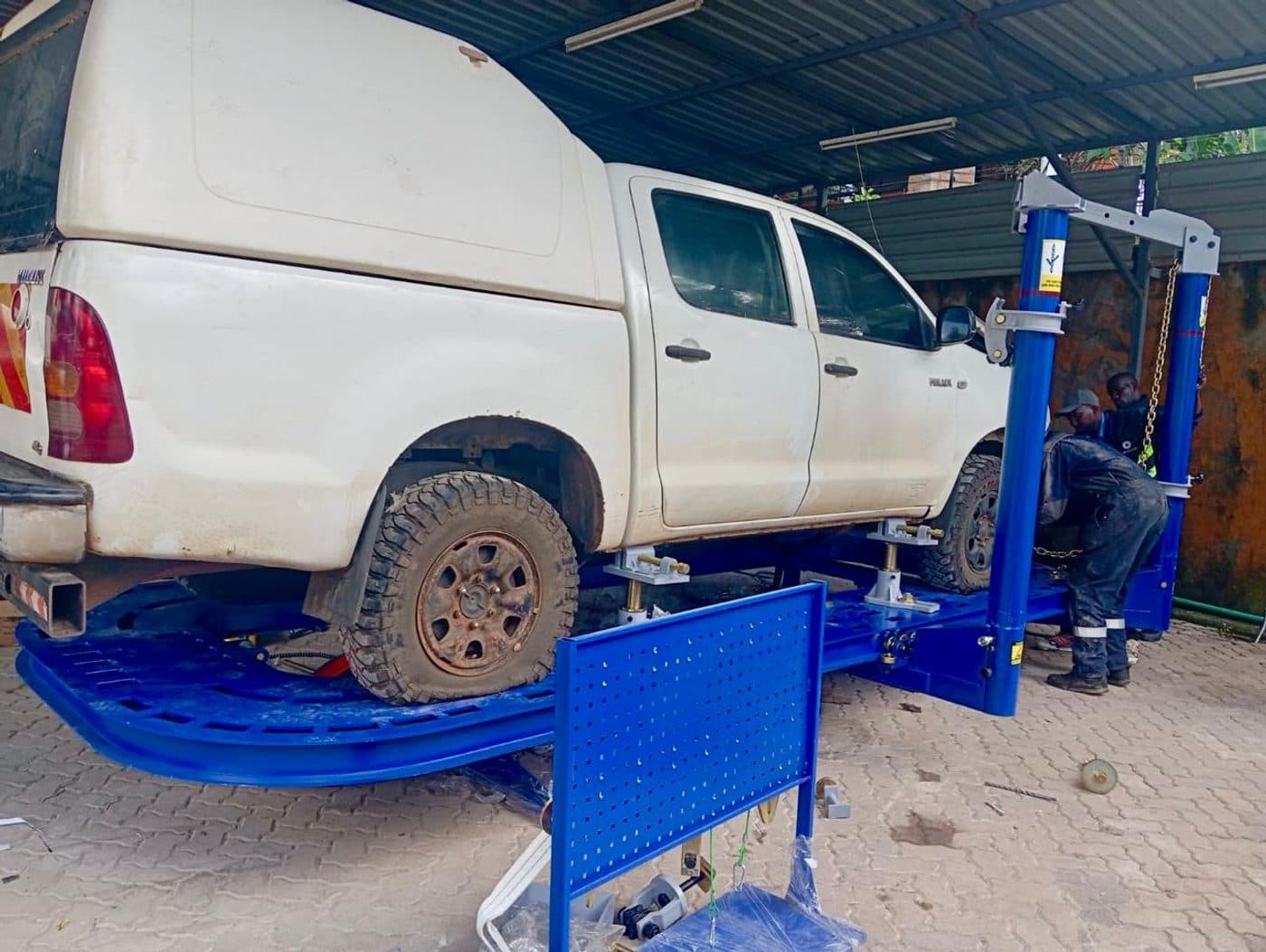 A pickup raised on a Roadbuck two-post lift while a technician works underneath